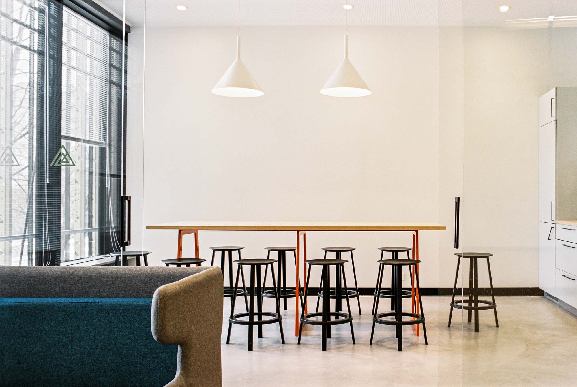 Small kitchen with wooden table black seats and large windows