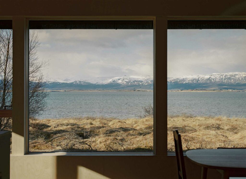 Large windows overlooking a lake and the snowy mountains