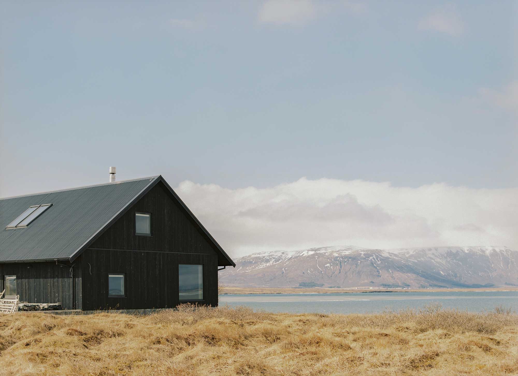 Black summer house in Iceland with snowy mountains in the background
